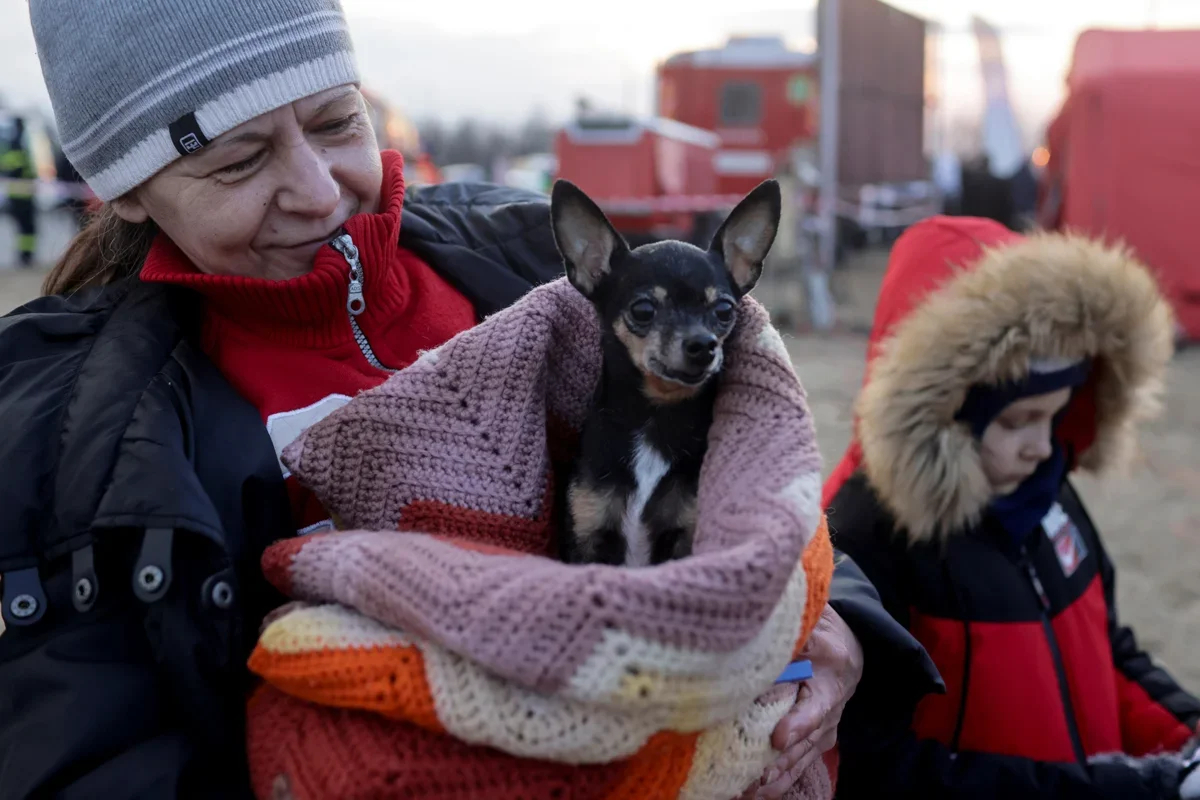 A woman holds a dog as she watches refugees from Ukraine crossing the Ukrainian-Slovak border, Slovakia, 3 March 2022. Photo: Lukasz Glowala / Reuters / Scanpix / LETA